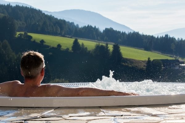 val-di-funes-september-28-man-from-behind-in-the-hot-tub-with-background-the-alpine-valley-of-the-600x400